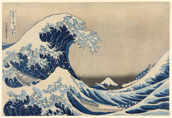 A crashing wave rises above small boats with Mount Fuji in the distance.